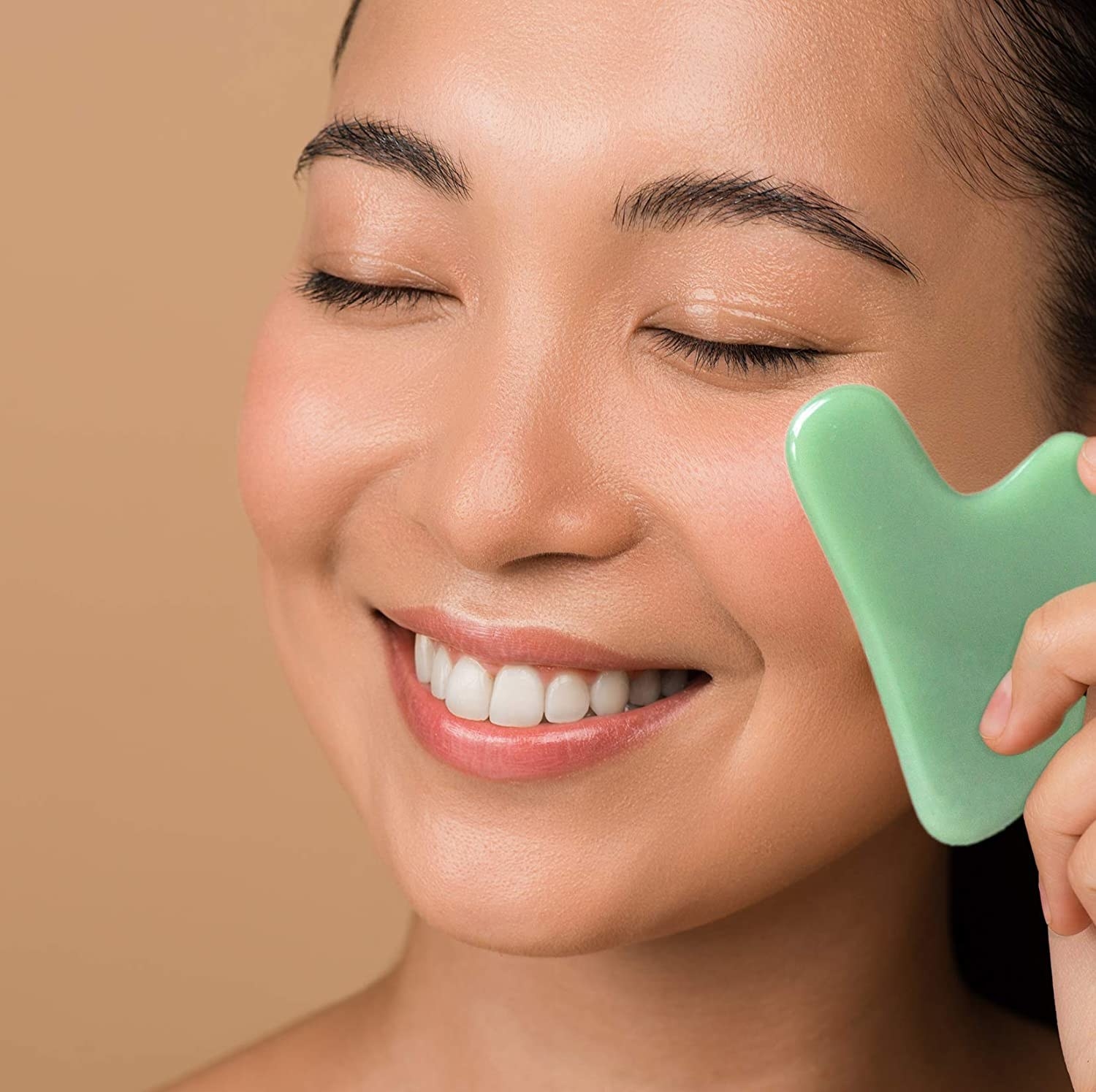 A person using a Gua Sha tool on their face