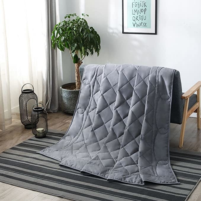 A weighted blanket draped over a chair in a trendy room