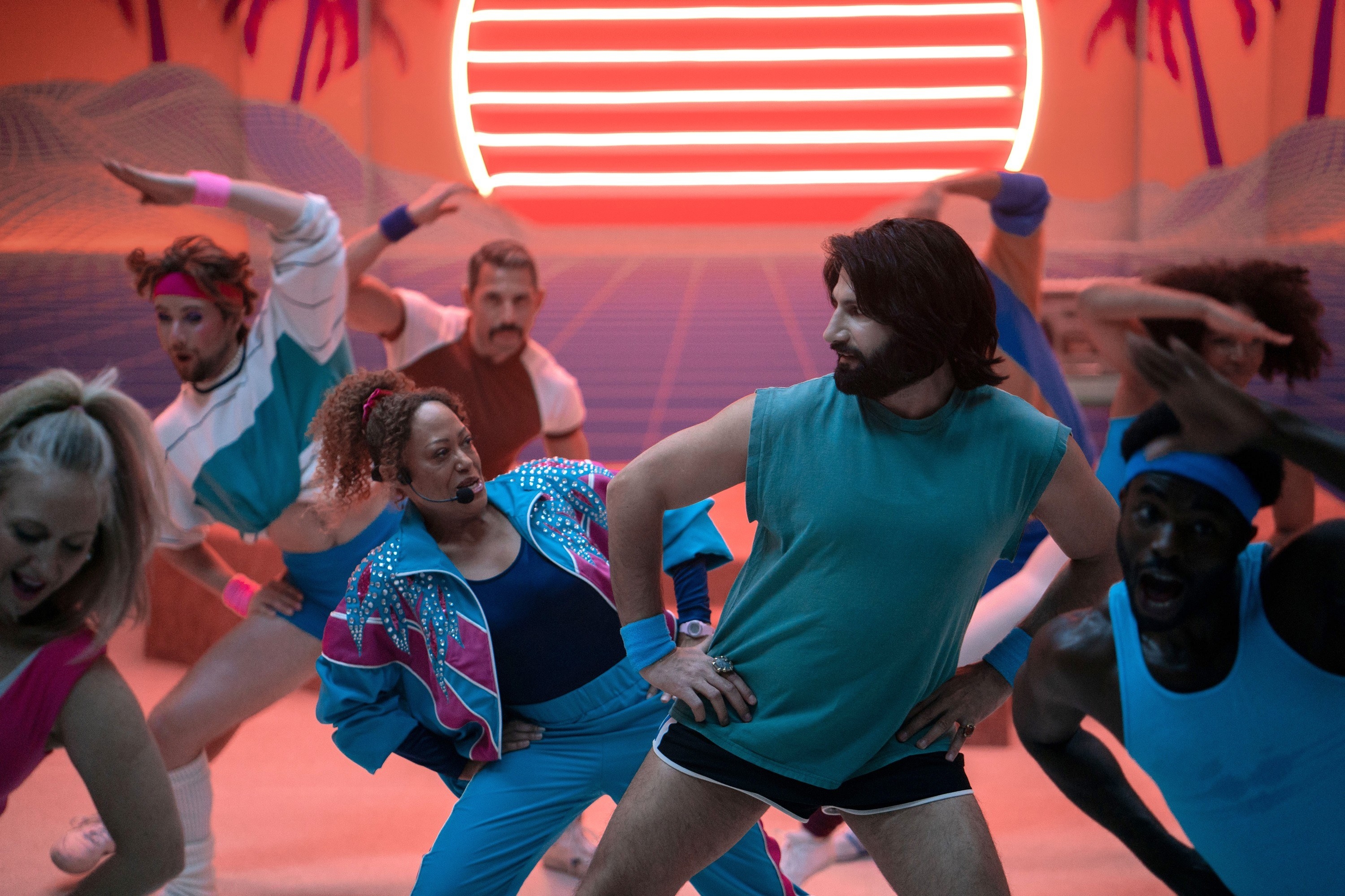 Nandor wears a blue muscle tank top and short shorts, exercising in a group