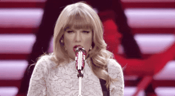 Taylor shaking her head side to side behind a microphone.