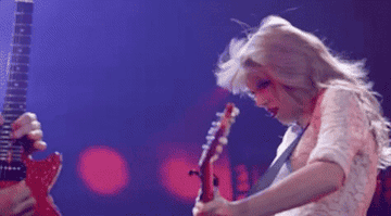 Taylor whipped her hair back while playing guitar, in slow motion.