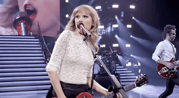 Taylor playing guitar and singing on stage.