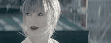 Taylor Swift looking behind herself with a happy expression.