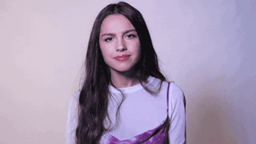 Olivia Rodrigo shrugging and looking confused/irritated