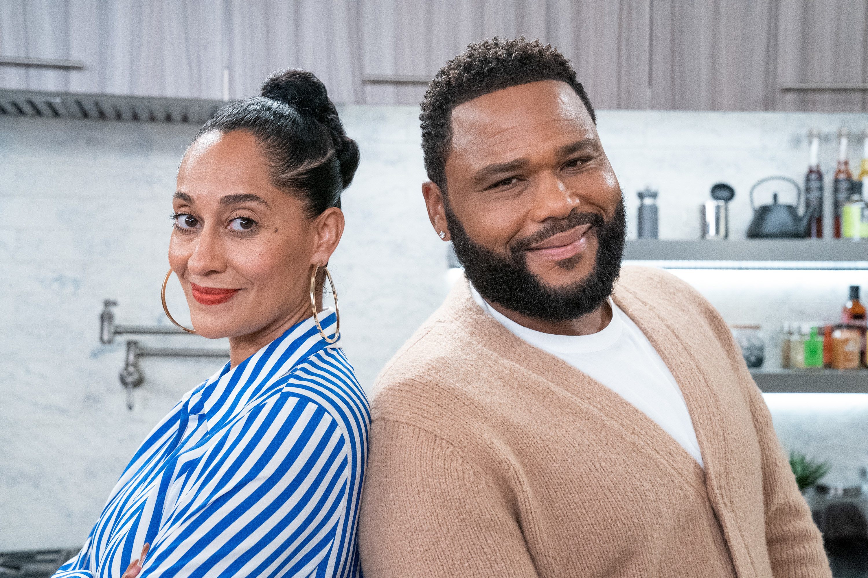 Tracee and Anthony smile while standing back to back