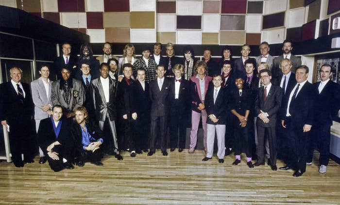 Phil Collins stands with a large group of musicians as well as Prince Charles and Princess Diana