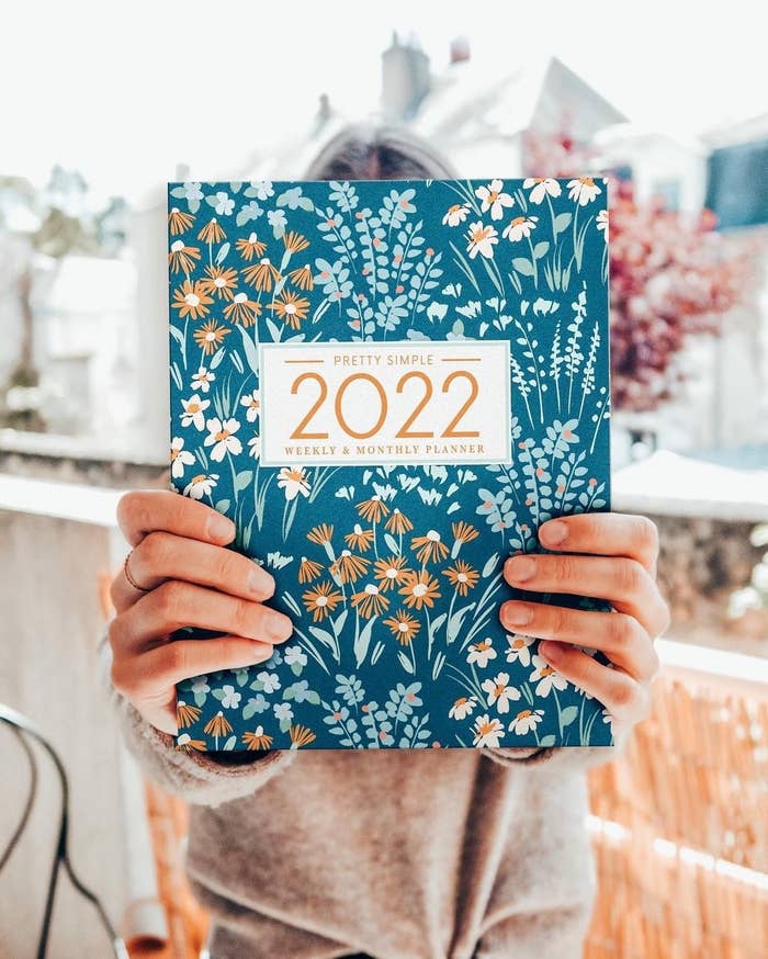 A person holding up a planner with a floral print on the cover