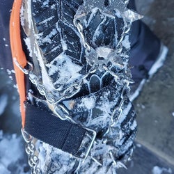 Close up of the bottom of a reviewer's snowy boot while wearing the grips