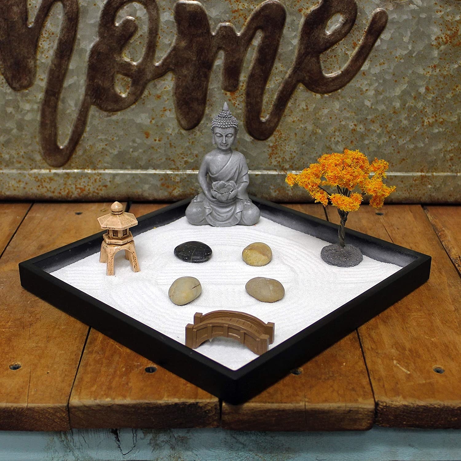 a zen garden with stones, sand, and a Buddha statue