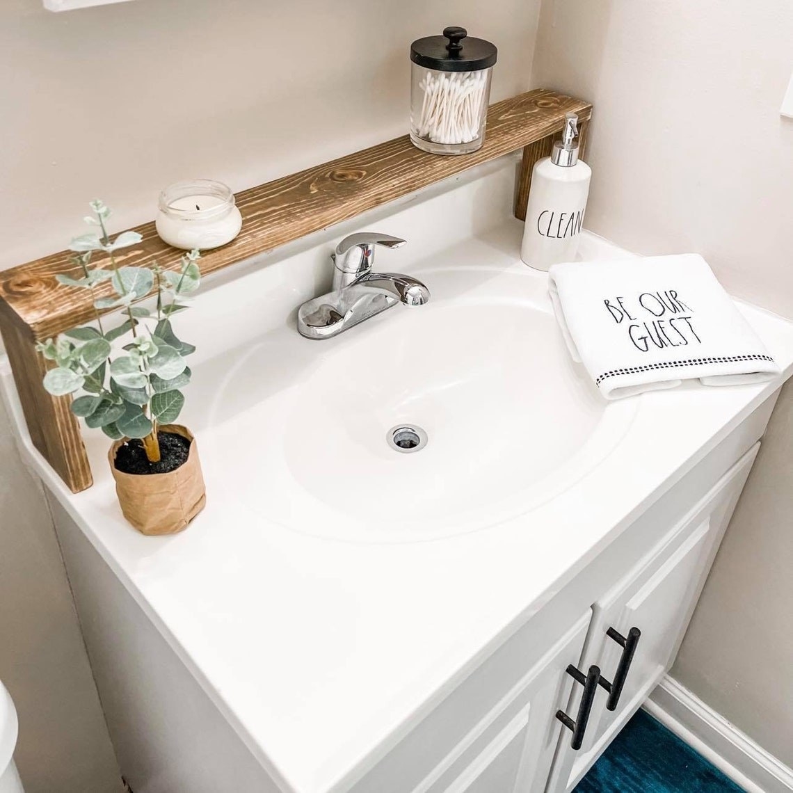 A rustic brown shelf placed over the back of a bathroom sink