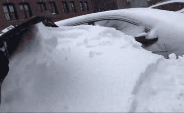 GIF of reviewer pulling a snow covered windshield cover off of their car to reveal a clean windshield