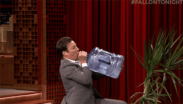 Jimmy Fallon drinking from a water cooler and falling over