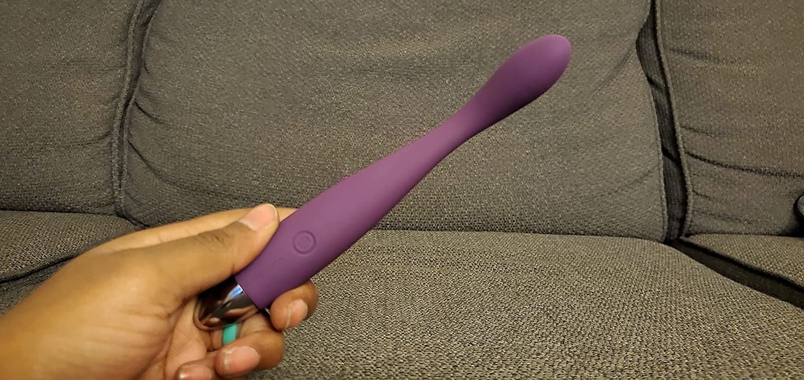 Reviewer holding slim purple vibrator with curved tip