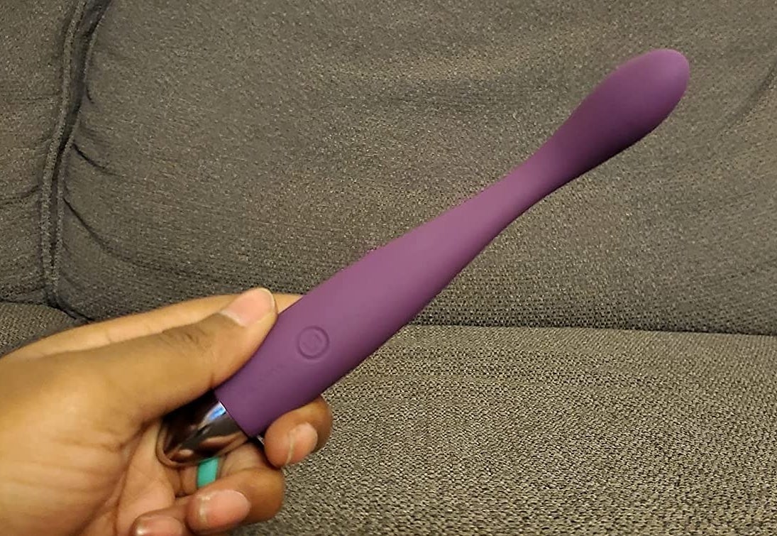 Reviewer holding slim purple vibrator with curved tip