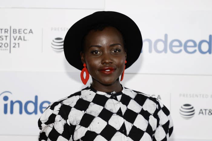 Lupita Nyong'o on the red carpet at the 2021 Tribeca Film Festival wearing a fedora and a checkered outfit