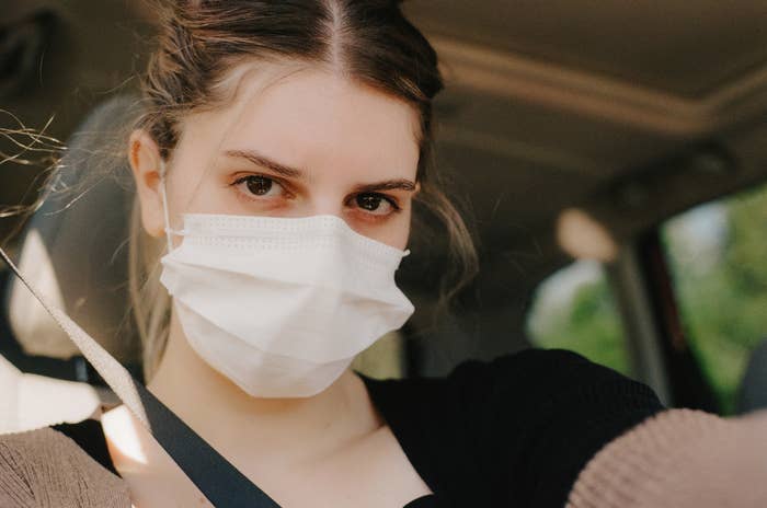 A selfie of Hannah wearing a face mask sitting in a car