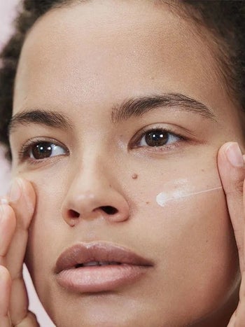Model applying the moisturizer to their face