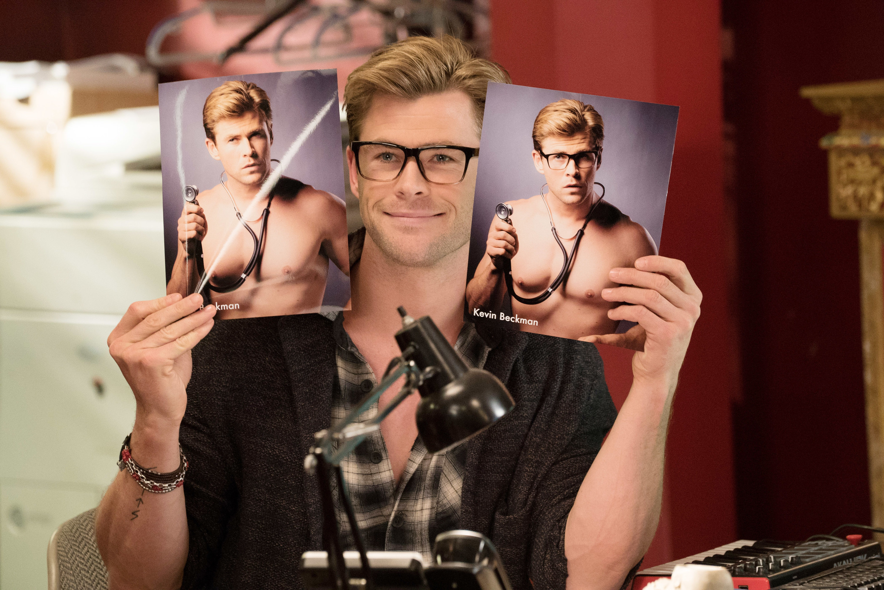 Kevin holding two mildly different headshots of himself as a shirtless doctor