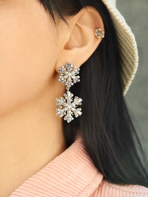 a model wearing a hanging earring featuring two snowflakes