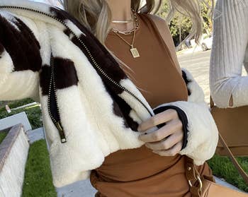 reviewer wearing initial pendant with brown top and furry jacket