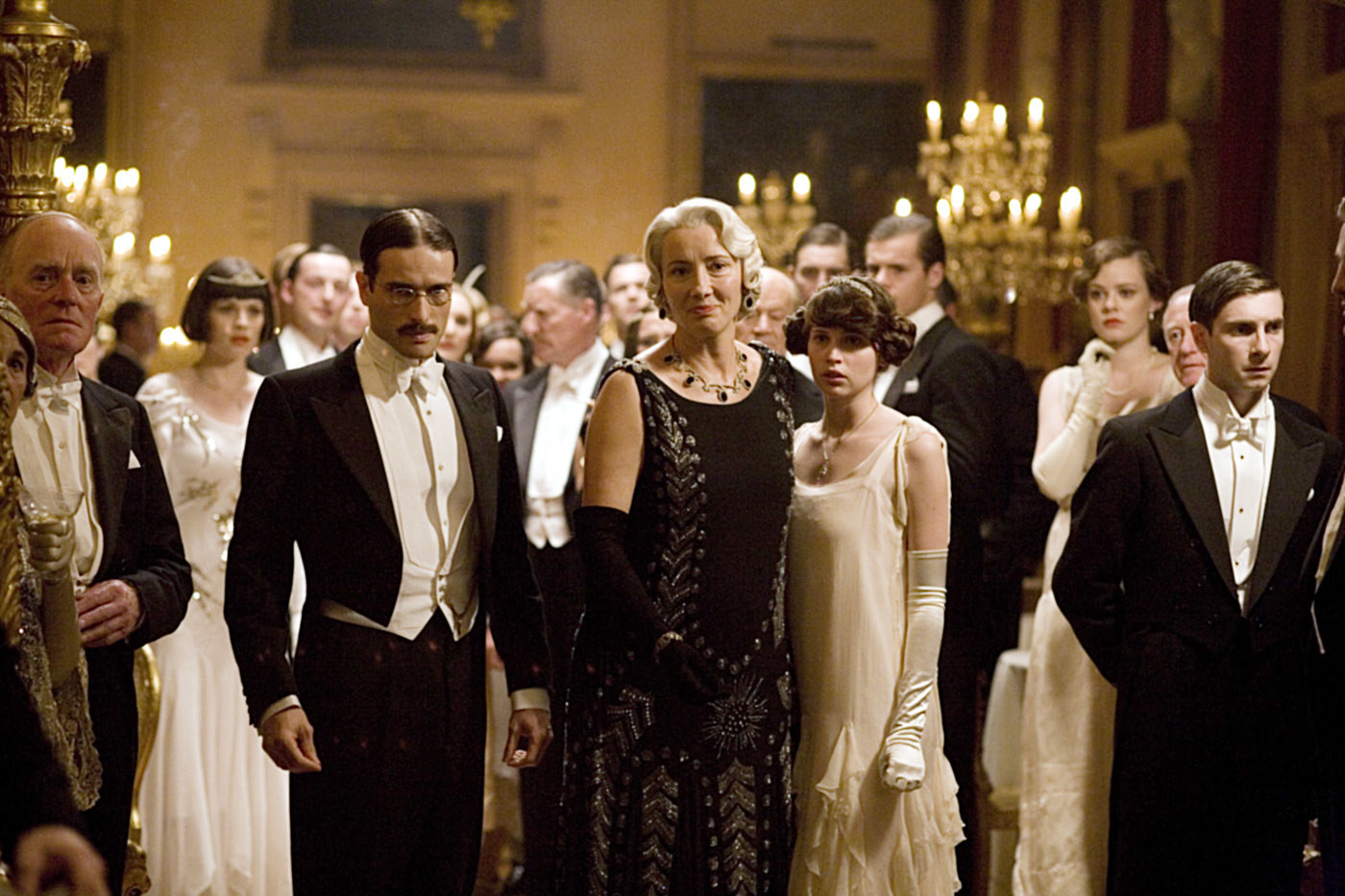 A group of people in elaborate formalwear at a ball, with Thompson in center