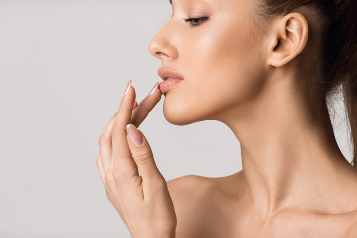 A woman with enhanced lips, touching them with her hand