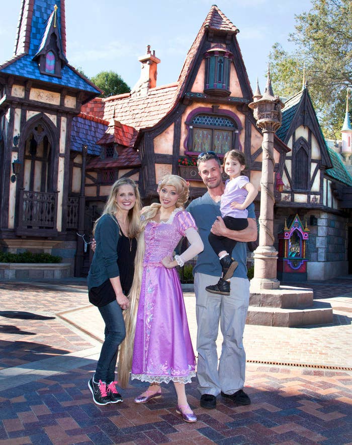 the couple are holding their daughter in disney world