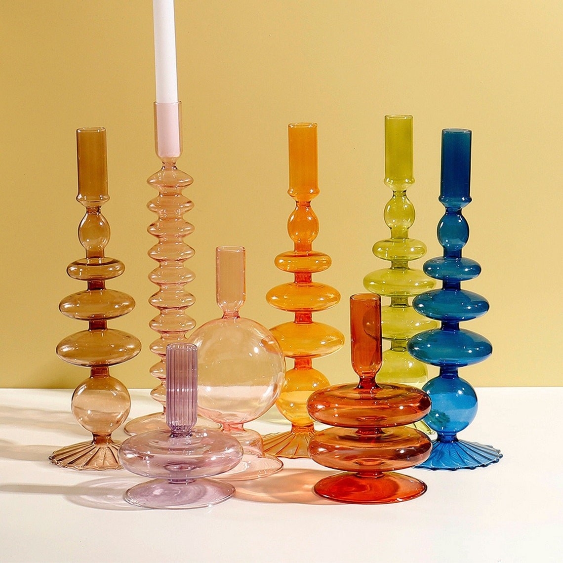 various candle sticks in different glass colors with various bubbles and curves