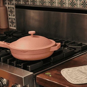 A gif of someone cooking in the pink pan, using the the steamer to make food