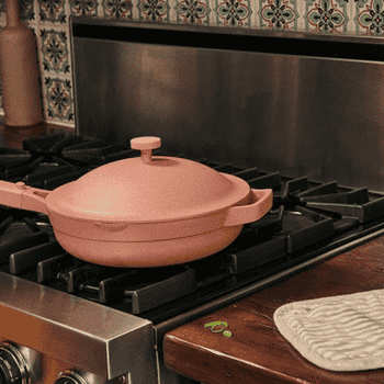 A gif of someone cooking in the pink pan, using the the steamer to make food