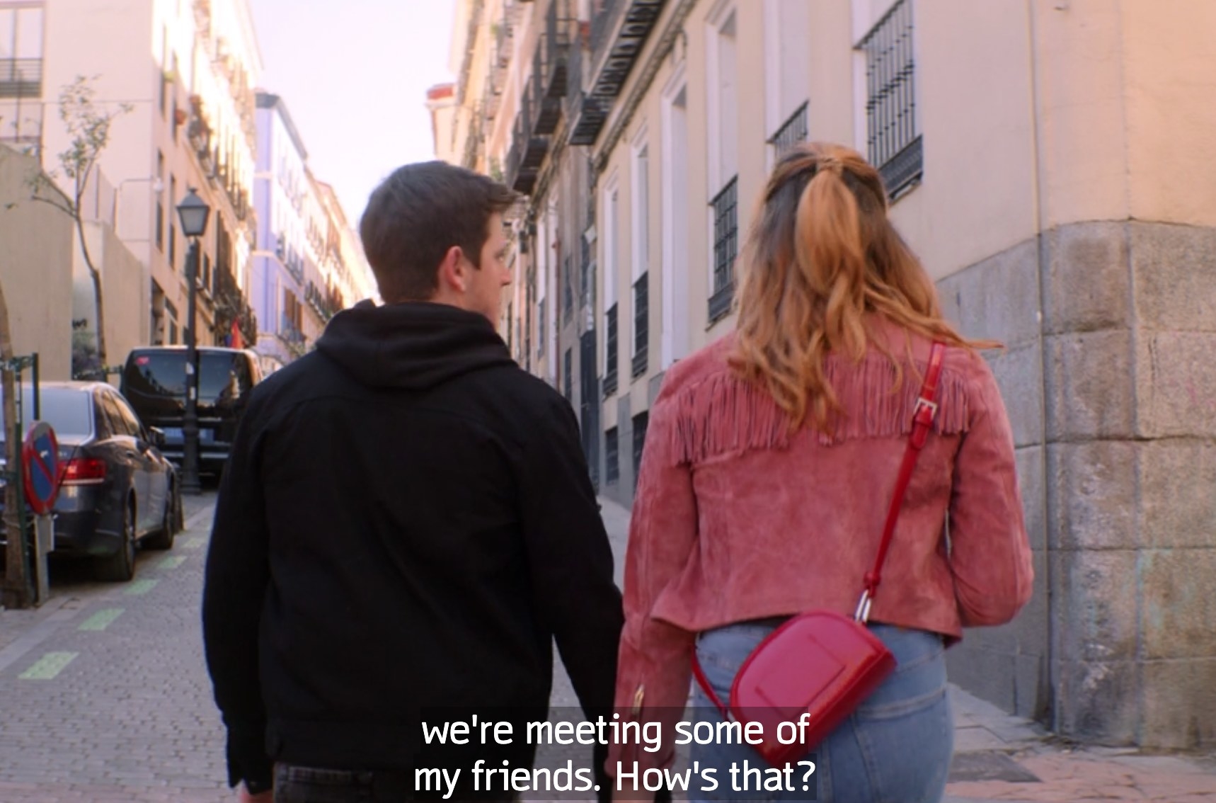 Inaki and Dafne walk down the street holding hands. 