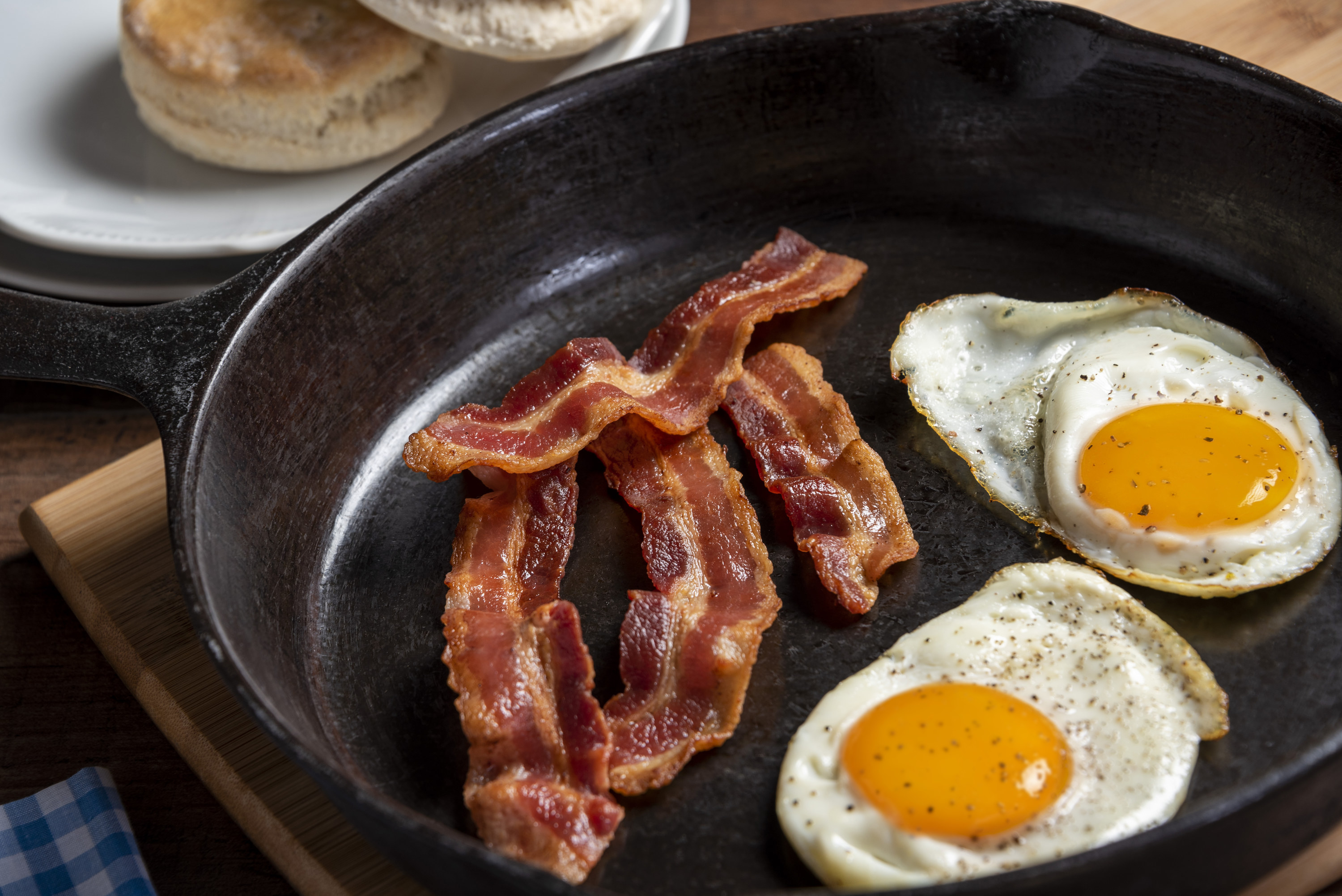 Bacon and eggs cooking in a cast iron skillet