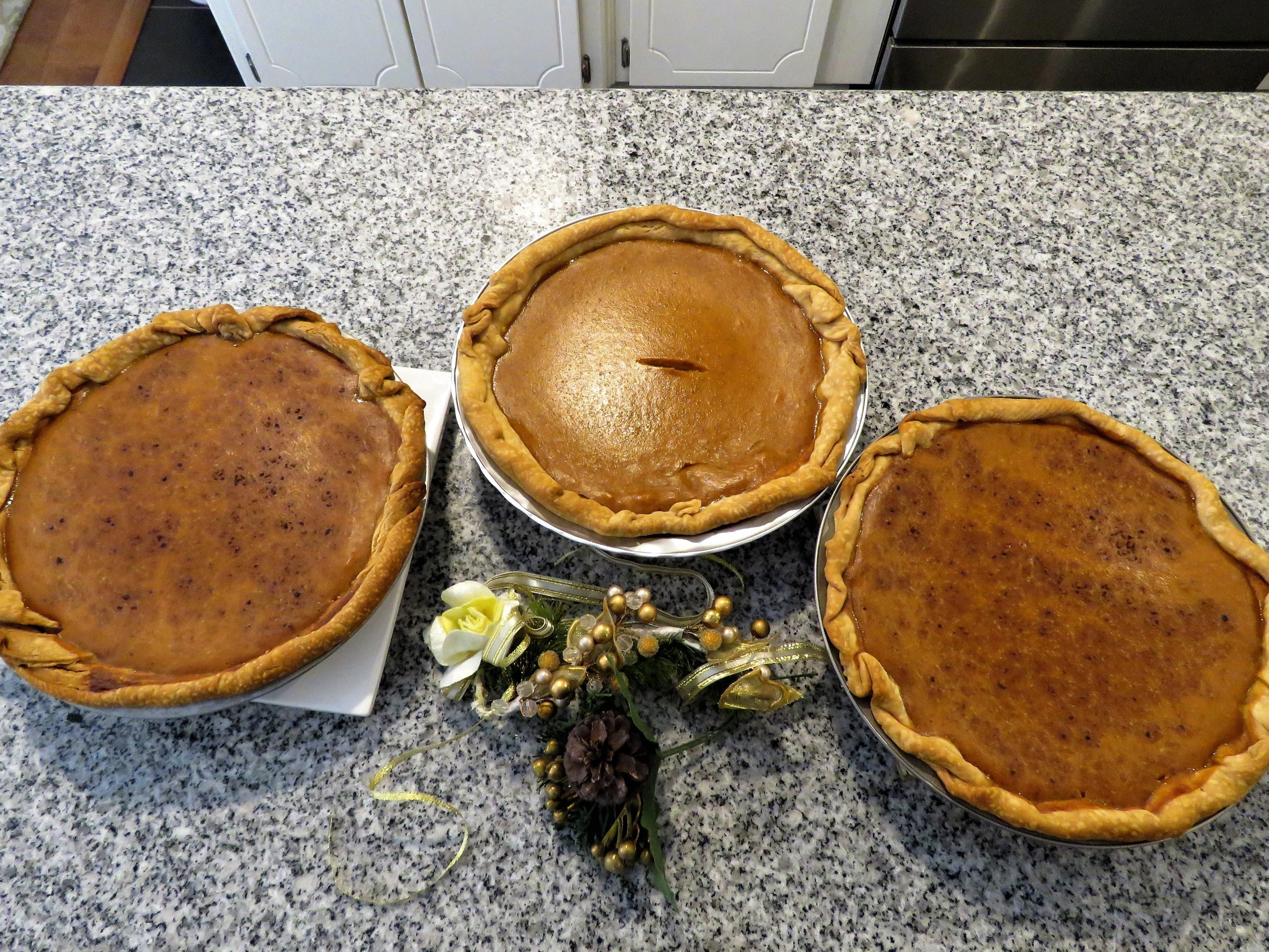 Three pumpkin pies on a counter