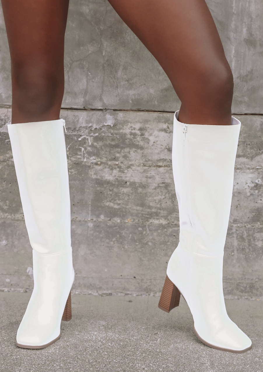Model wearing knee-high white boots with brown wood heel