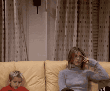 Ben Gellar sitting next to a defeated looking Rachel Green on a couch on