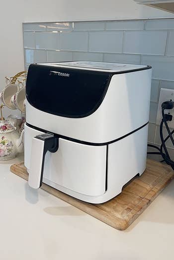 a reviewer shows the white air fryer on their countertop