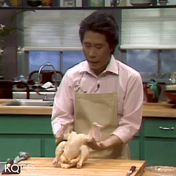 Man on cooking show flipping a chicken on a cutting board