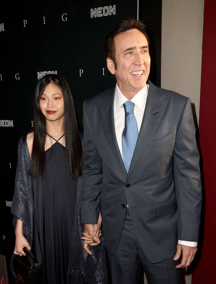 Cage holds hands with Riko Shibata at an event