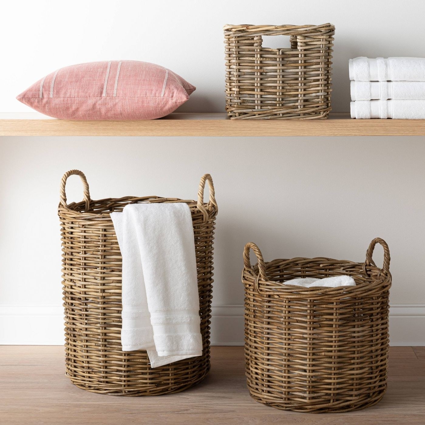 brown/gray round rattan baskets on the floor with towels inside