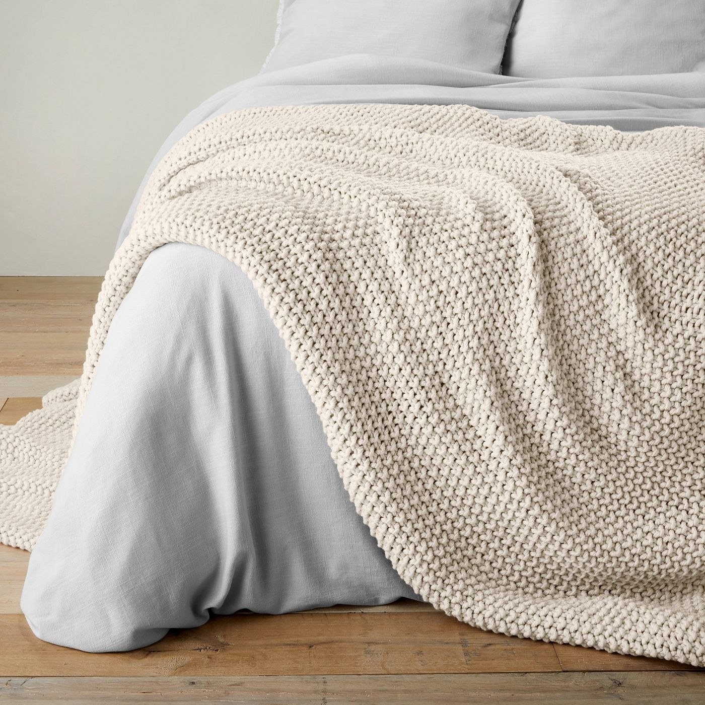 cream chunky knit blanket draped on a bed