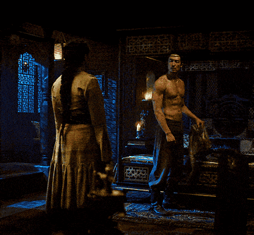 Lan Mandragoran putting his shirt down while walking to Nynaeve