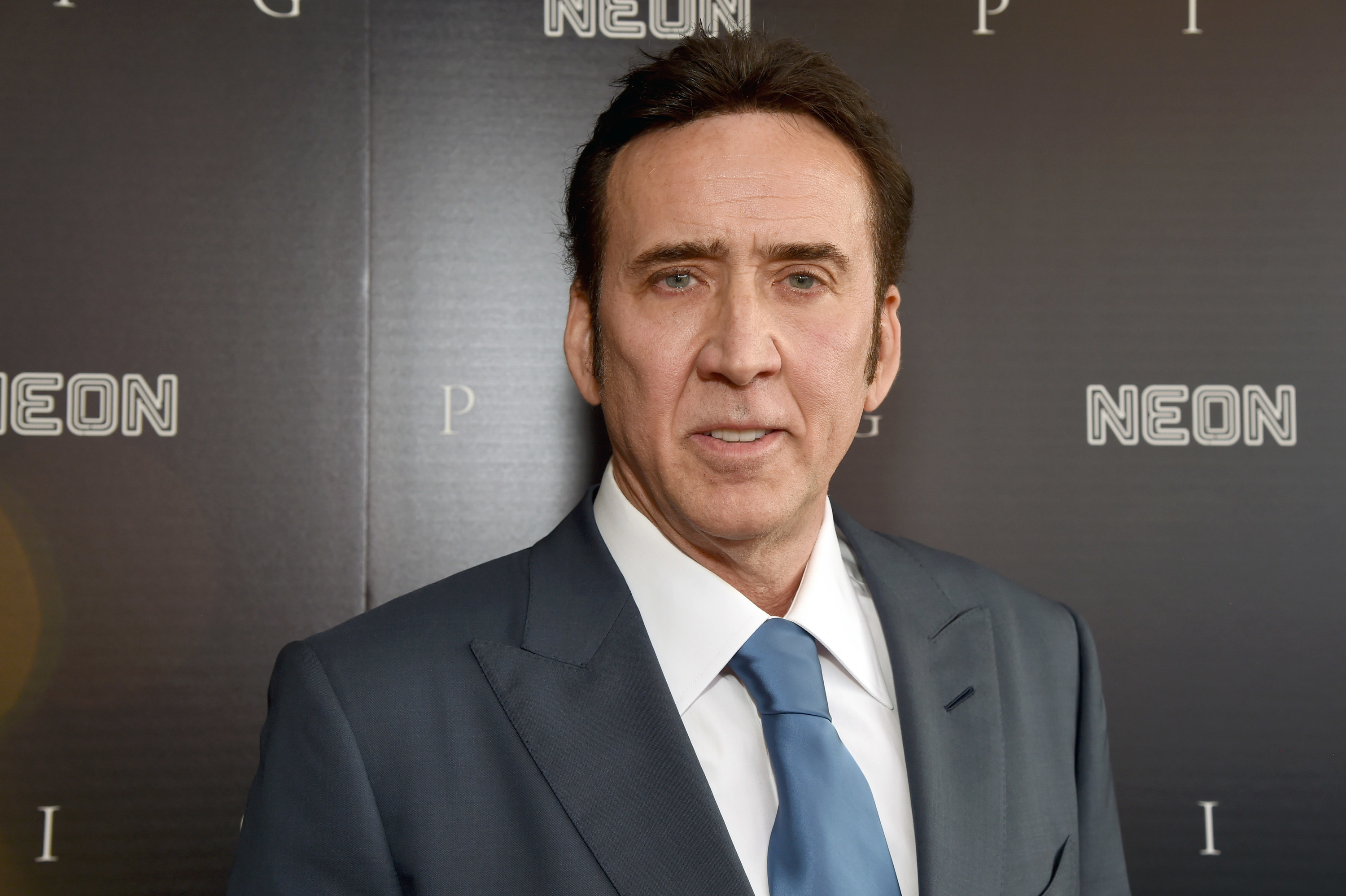 Cage looks at the camera at a step-and-repeat