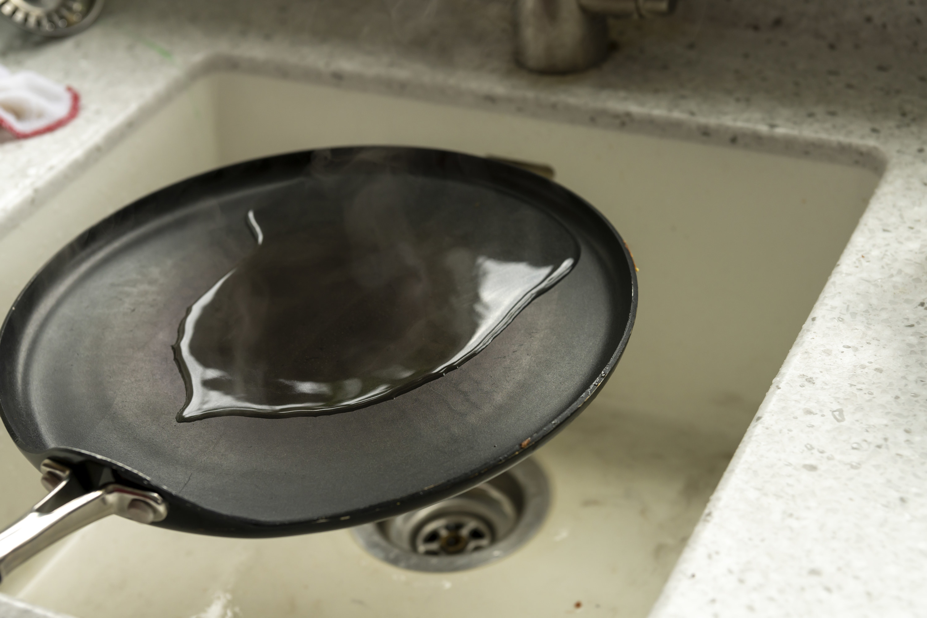 Cast iron skillet with water on it, about to be washed in the sink