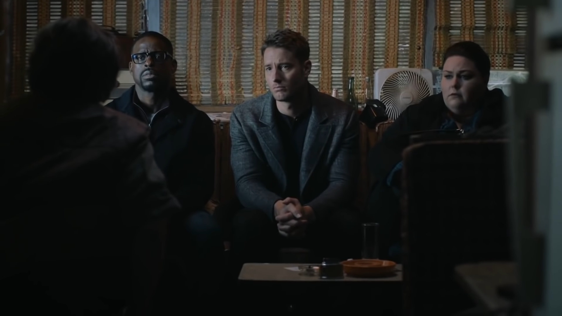 Randall, Kevin, and Kate sit on a couch as adults, listening to their uncle Nicky speak