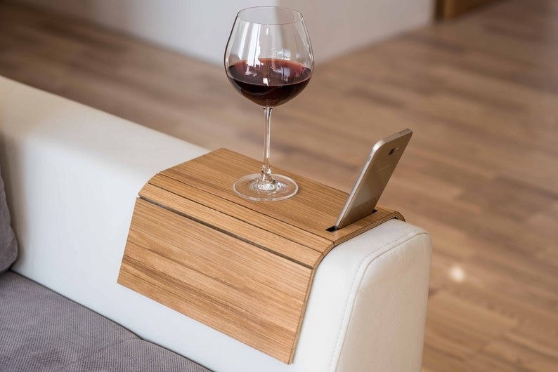 the wood couch arm with wine and a phone resting on top