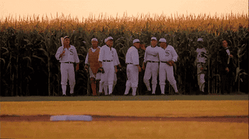 Baseball players gathered in a corn field.