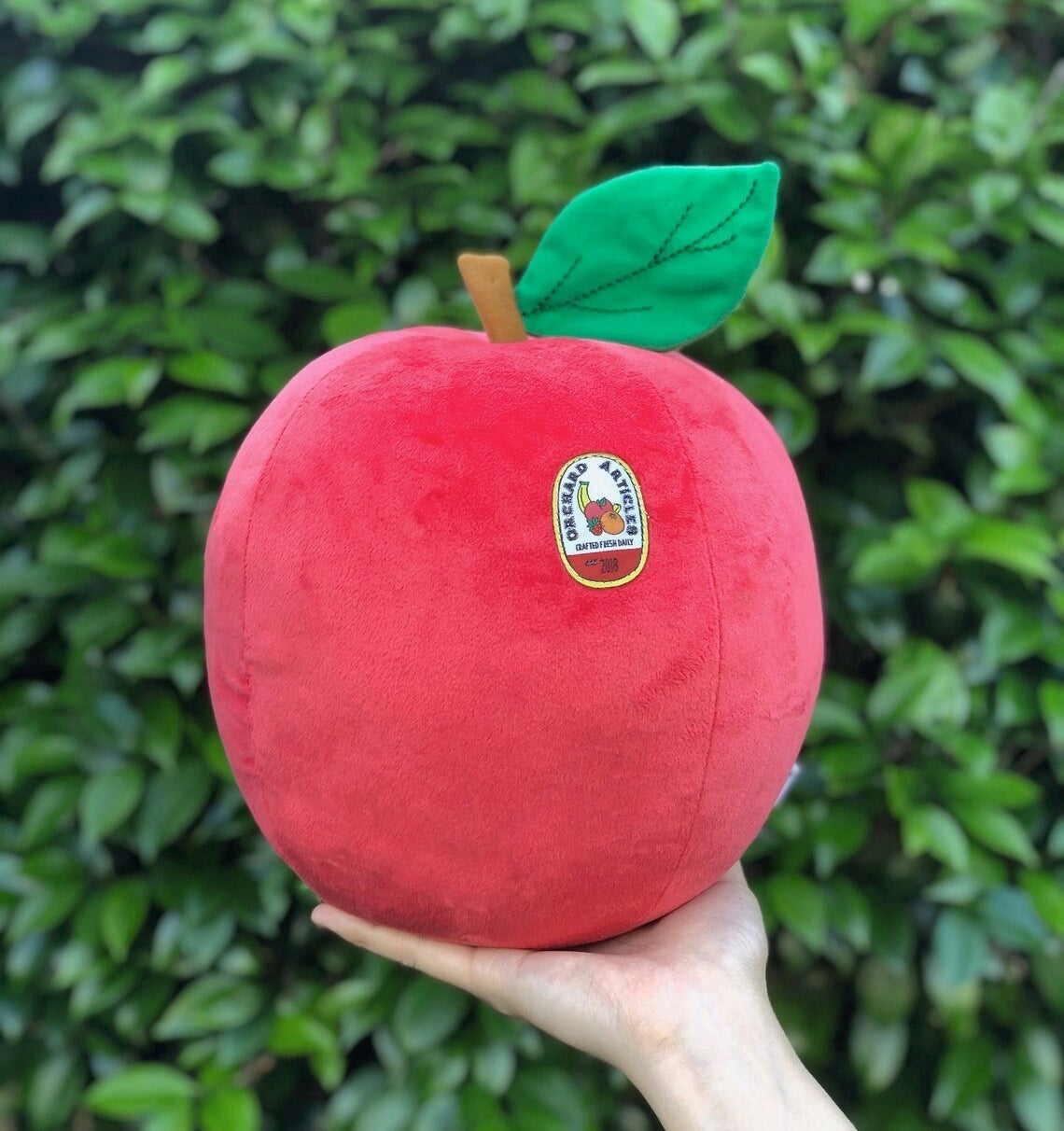 a round plush apple with a sticker patch on it