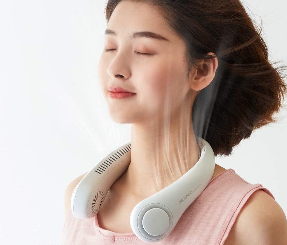 A person wearing the portable neck fan, demonstrating that the air flows all the way around their head