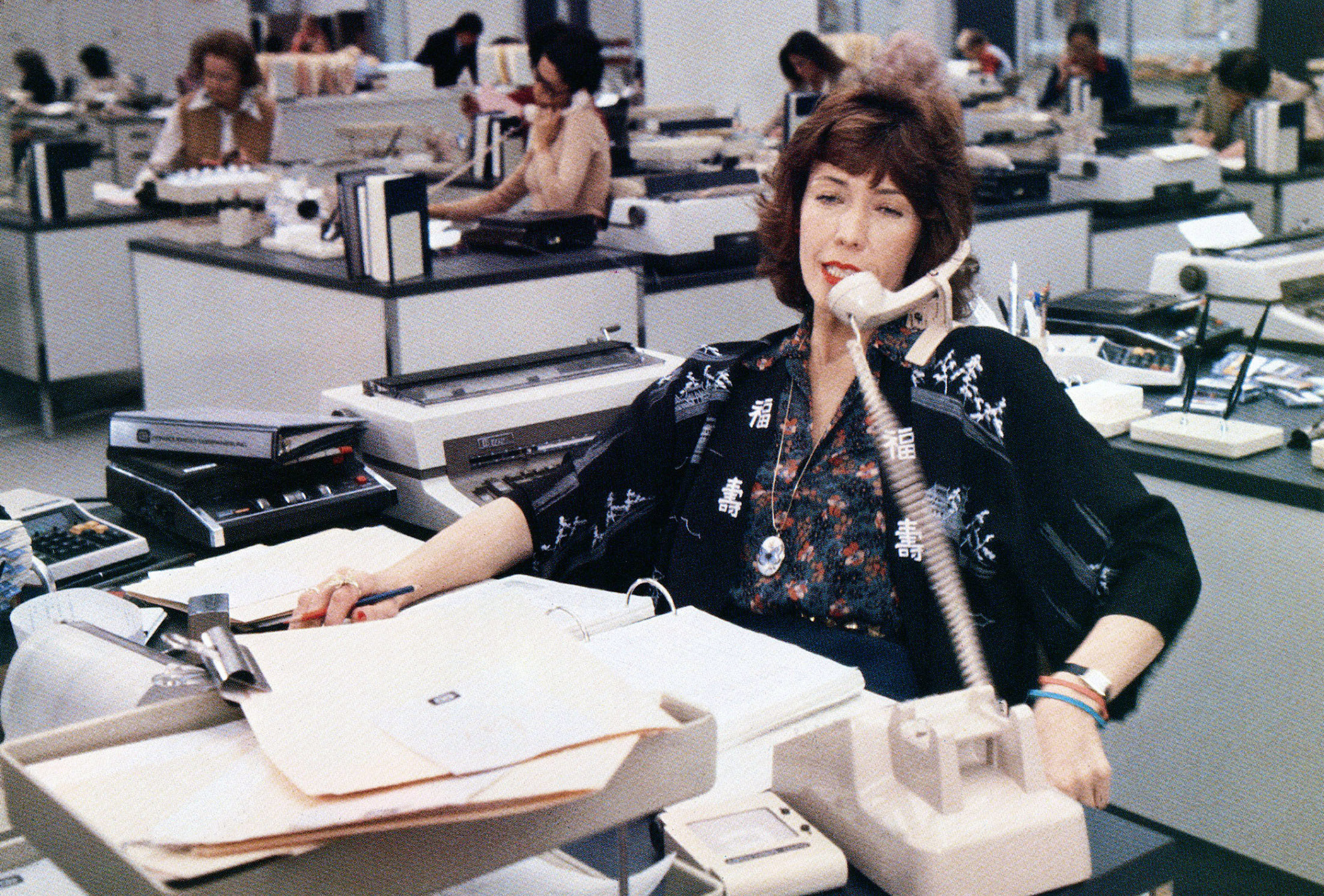 Lily Tomlin as a secretary on a crowded office on the phone