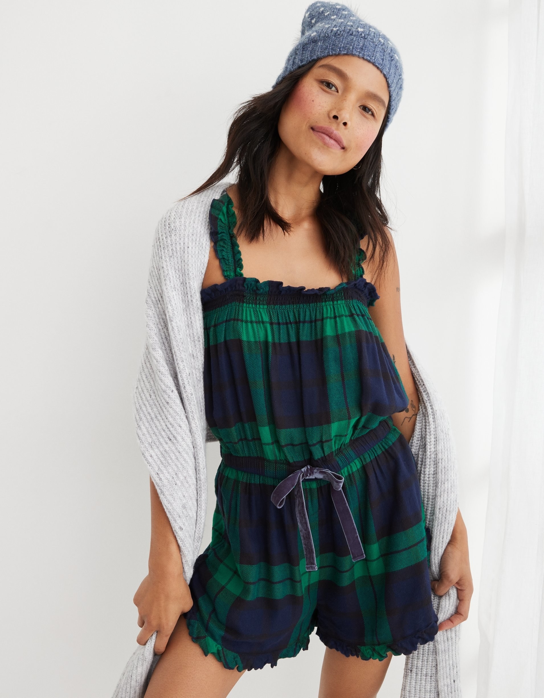 model in the green and blue plaid ruffle-edged short tank top romper with a velvet waist tie